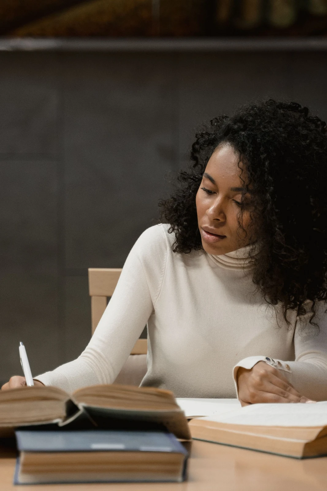 A woman writing beside shelves of books